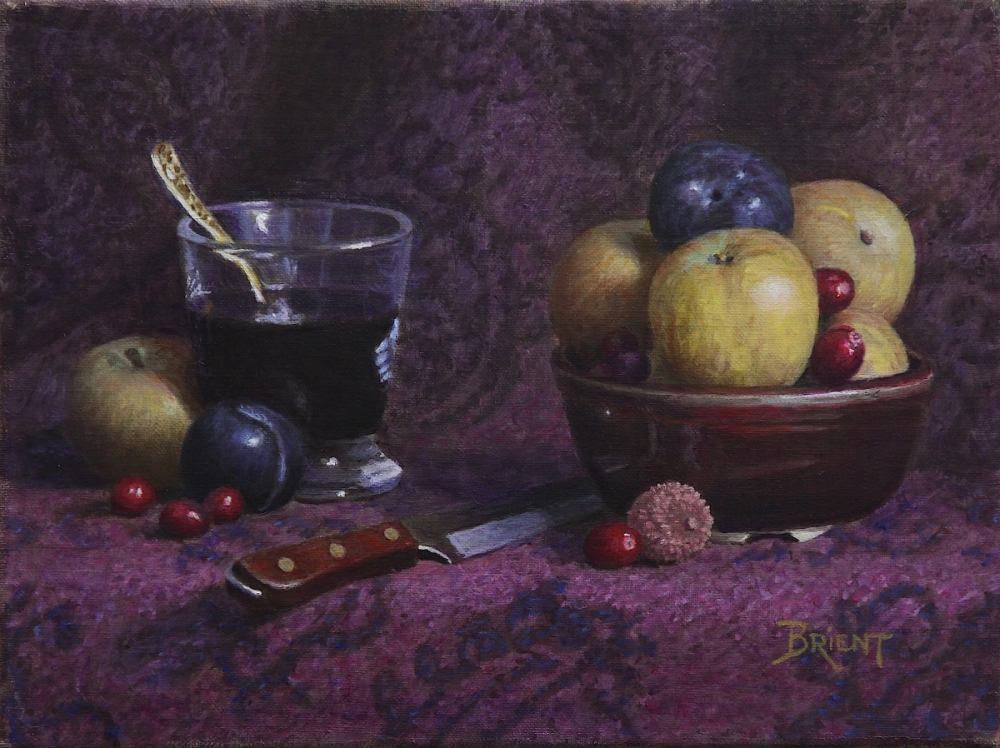 A Bowl of of yellow apples and other fruits, a litchi, some cranberries, a glass of red wine on a pattern fabric