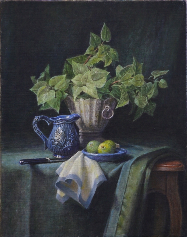 A green plant, a plate of limes a small blue jug