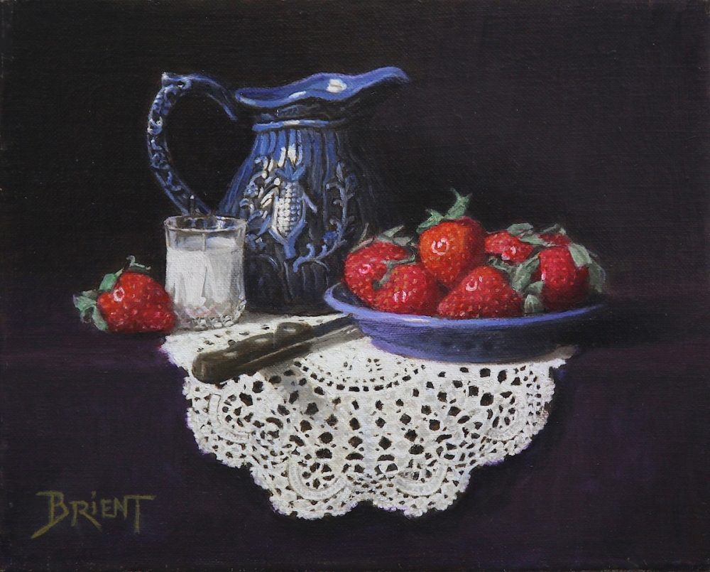 Small blue pitcher, a plate of strawberries, a small glass of milk  on a lace doily 